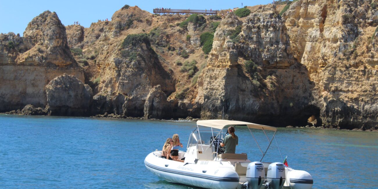 Private boat cruising past rock formations at Ponta da Piedade